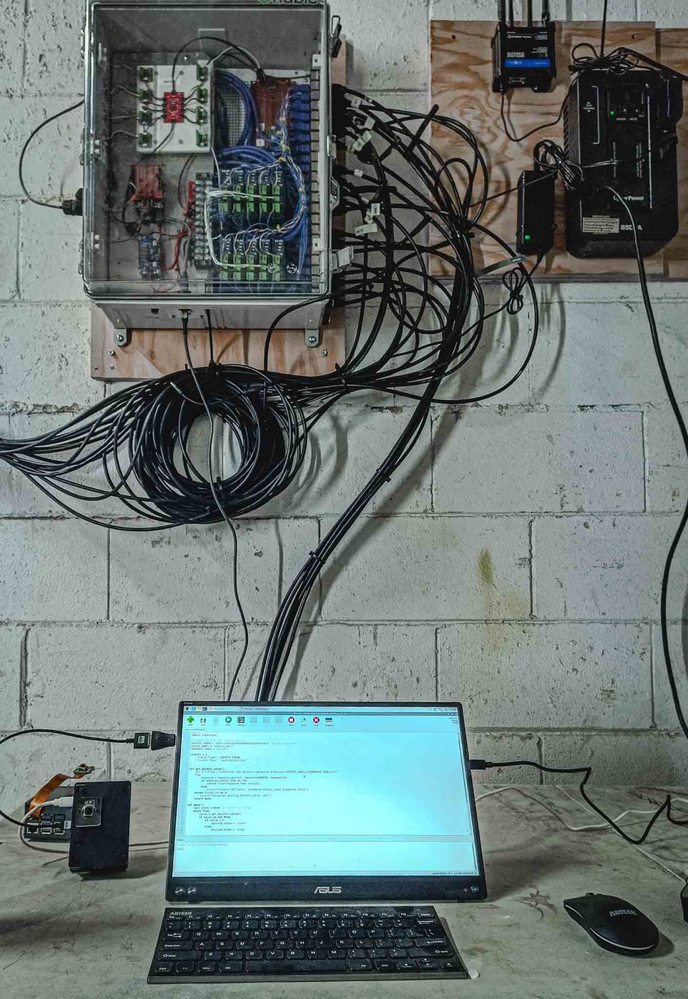 Data acquisition enclosure on a block wall with sensor cables running down to a laptop