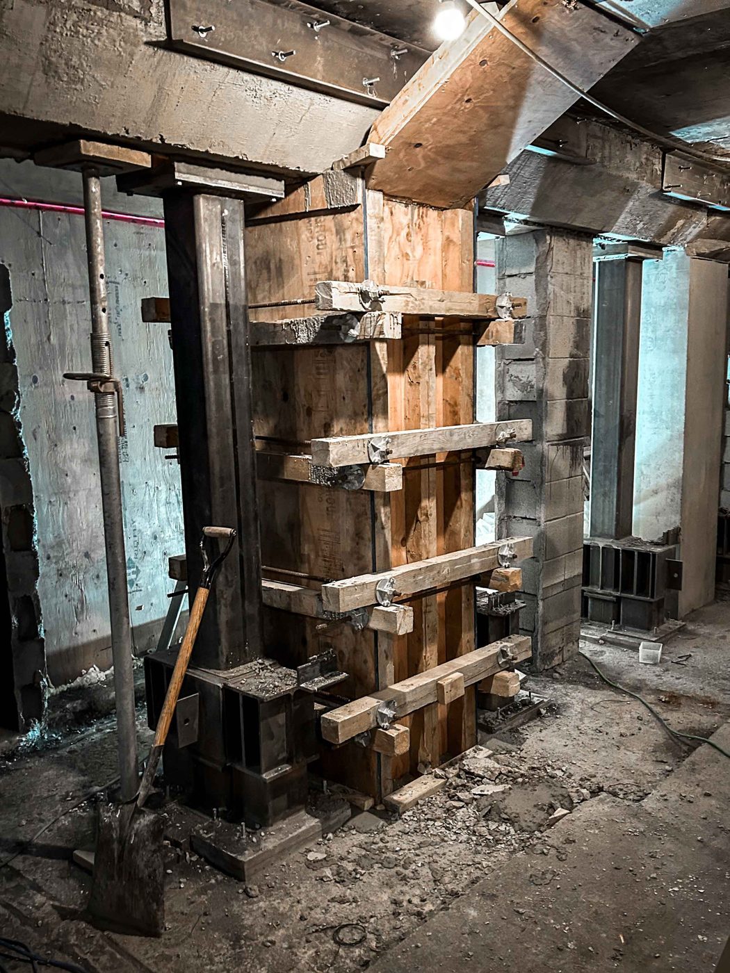 Timber formwork clamped around a column between steel shoring posts